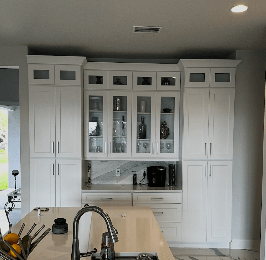 White Shaker coffee bar wall with tall pantry cabinets, glass-front uppers, a marble backsplash, and drawers below the counter