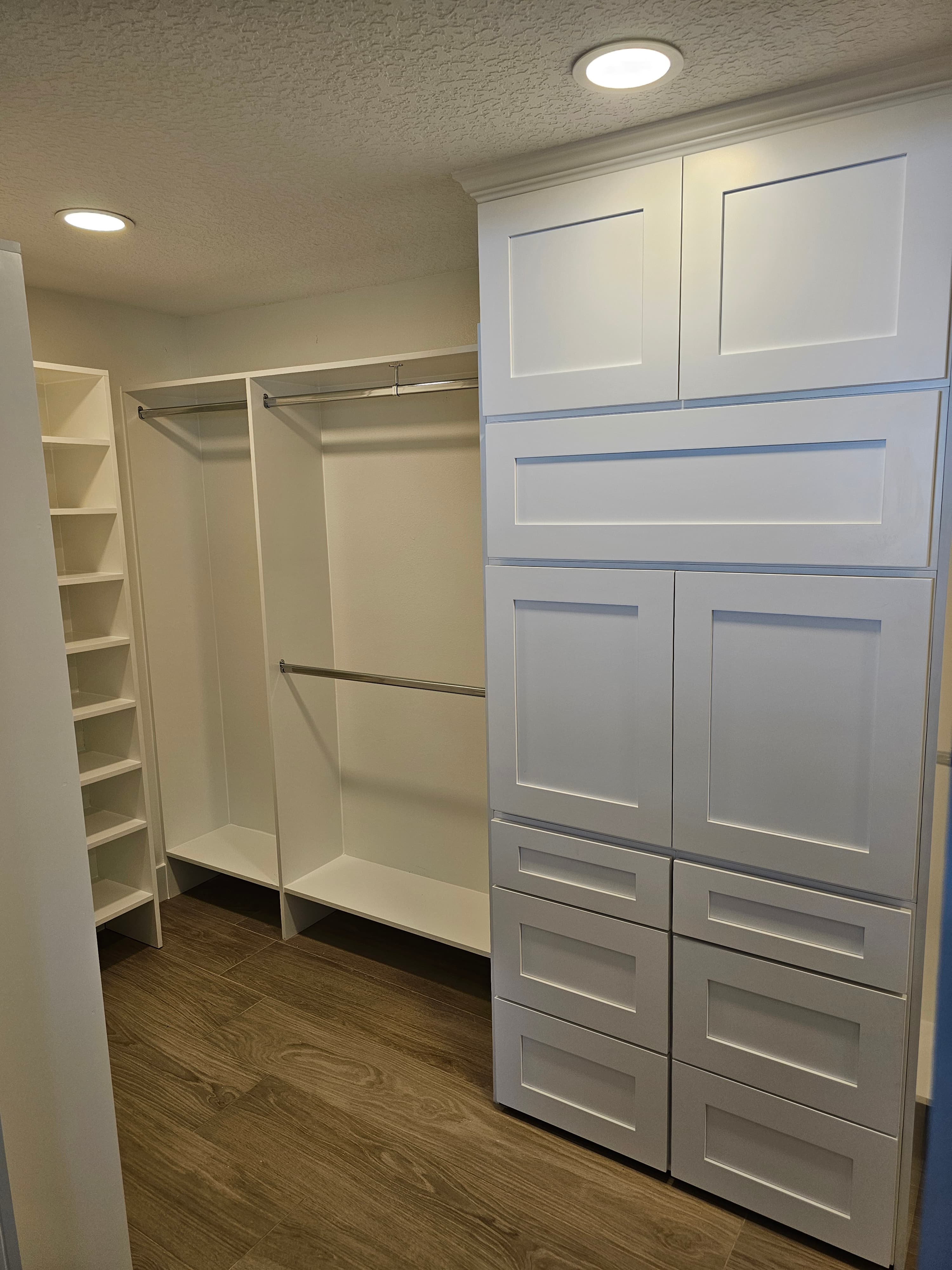 Walk-in closet with white Shaker-style cabinets, a drawer bank, open shoe shelving, and double hanging rods