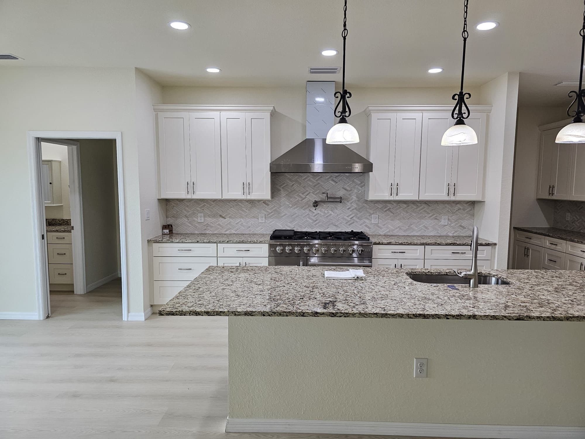White Kitchen with Granite Island and Pendants