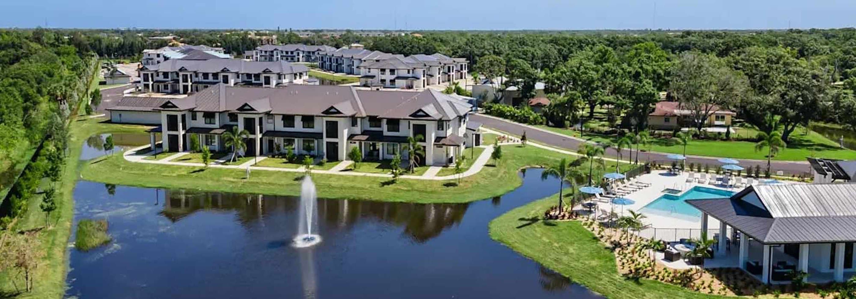 Aerial view of The Waterfront on Hatchett Creek apartment buildings, pond and pool in Venice, Florida